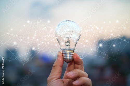 Businessman holding glowing lightbulb with drawing brain and connection line