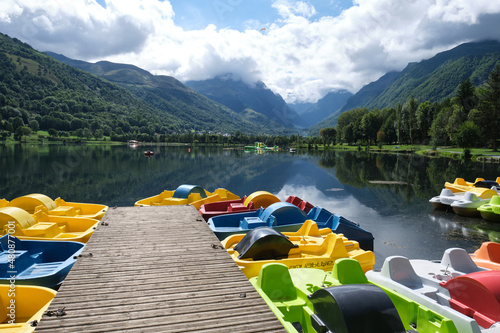 Fototapeta Group of colorful pedal boats next to the wooden pier of Lake Genos ,Loudenvielle, France
