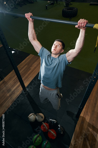 Fotografi Strong young man doing dead hang exercise