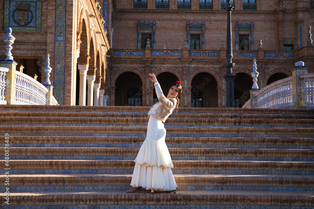 Obraz premium Flamenco dancer, woman, brunette and beautiful typical spanish dancer is dancing and clapping her hands on the stairs of a square in seville. Flamenco concept of cultural heritage of humanity.