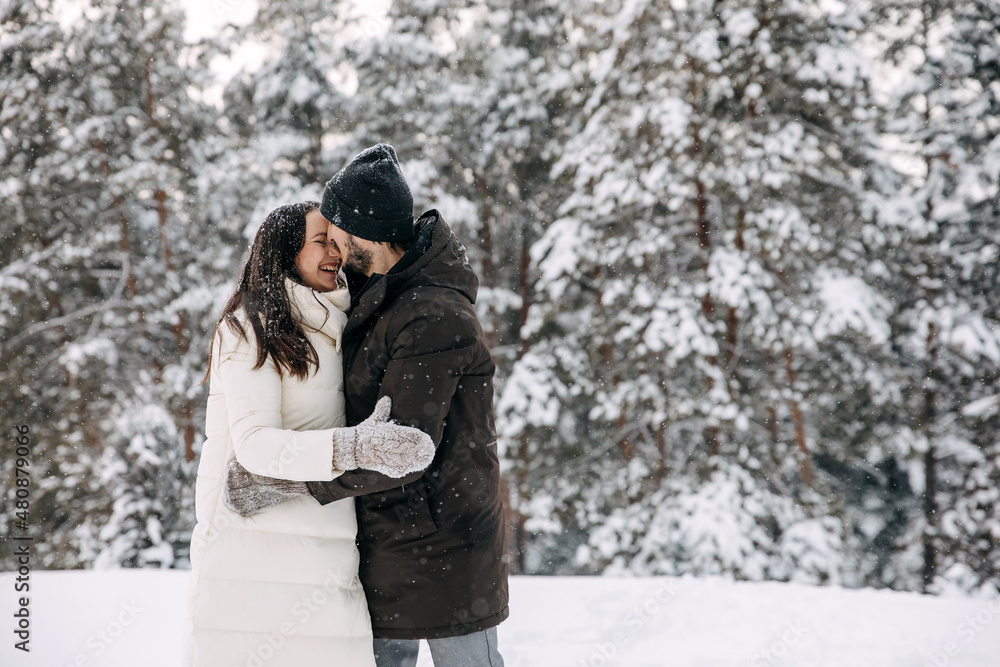 Happy couple hugging and smiling on a cold snowy winter day.