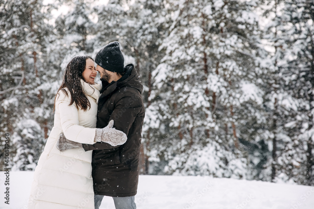 Happy couple of man and woman hugging on a snowy winter day on trees covered in snow background. Happy couple of man and woman hugging on a snowy winter day on trees covered in snow background.