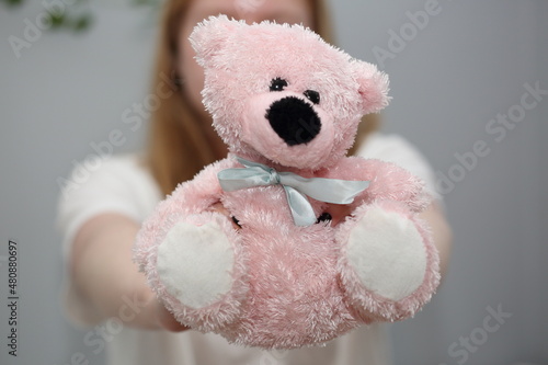 Cute pink teddy bear in girls hand close up