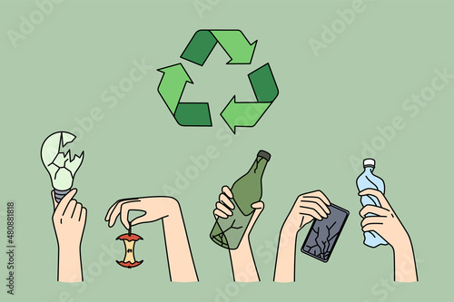 Recycling and ecological conversation concept. Human hands holding various trash lamp apple bottle electronics for recycling with symbol above vector illustration 