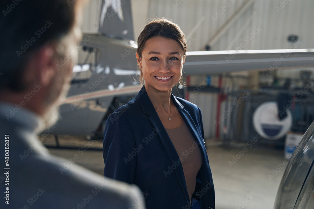 Joyful lady standing before man in aircraft hangar Joyful lady standing before man in aircraft hangar