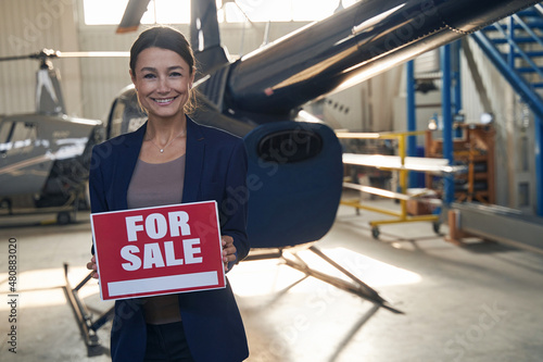 Cheerful aircraft hangar manager selling private helicopter photo