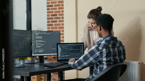 Two programmers doing high five hand gesture at desk with multiple screens running code celebrating successful algorithm. Software developers colleagues enjoying teamwork results in it agency
