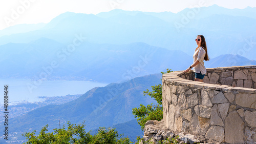Young tourist woman enjoying view of Kotor bay in Montenegro in mountains.