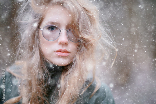 girl romantic portrait first snow autumn, snowflakes blurred background seasonal winter