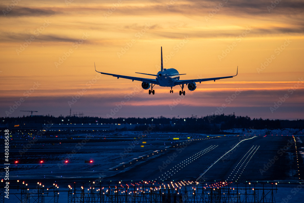 Airplane landing to airport runway in sunset - obrazy, fototapety, plakaty 
