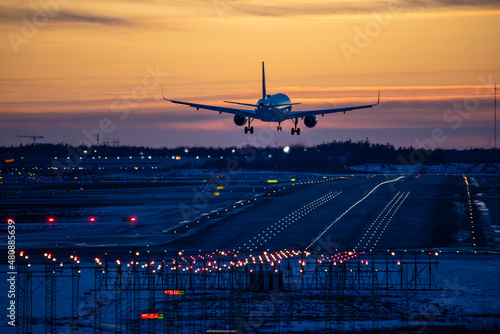 Airplane landing to airport runway in sunset