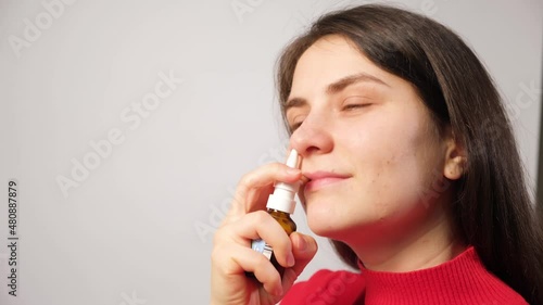 A female patient shoves a spray into the nose to treat rhinitis, an allergy with difficulty breathing photo