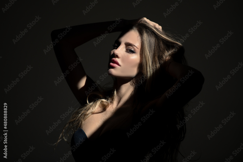 Naklejka premium Portrait of young attractive woman. Dramatic and sensual portrait of a beautiful girl isolated on a dark background in studio. Sensual girl with art shadow light.
