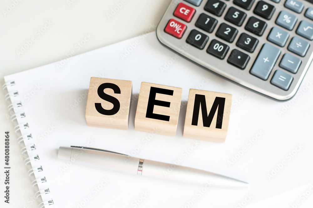 Fototapeta SEM word on wooden cubes on a notebook next to a calculator and a pen on the tab