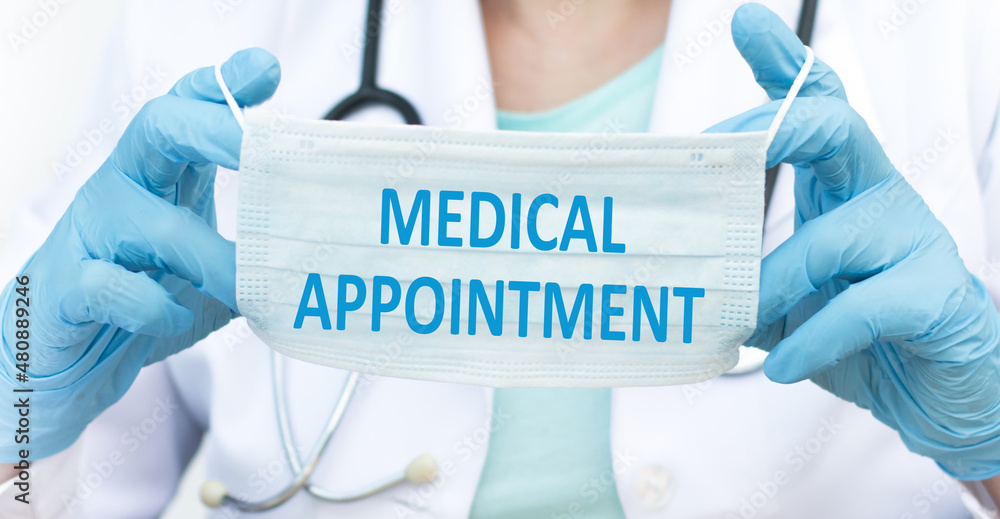 text MEDICAL APPOINTMENT on a blue protective mask in the hands of a doctor. Medical concept, text MEDICAL APPOINTMENT on a blue protective mask in the hands of a doctor. Medical concept,