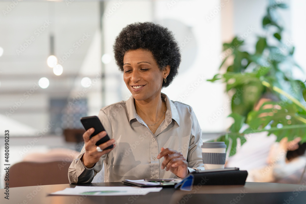 Smiling businesswoman using smart phone at office Smiling businesswoman using smart phone at office