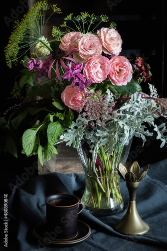 Studio shot of coffee cup and bouquet of Mini Eden roses, annual claries, Queen Annes lace, black-eyed Susans, silver ragwort, mint and dill photo