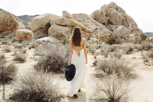 Woman in boho style walking with hat in hand in the Joshua Tree desert photo