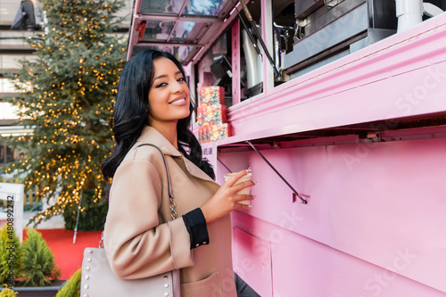 Smiling woman with coffee cup near pink concession stand