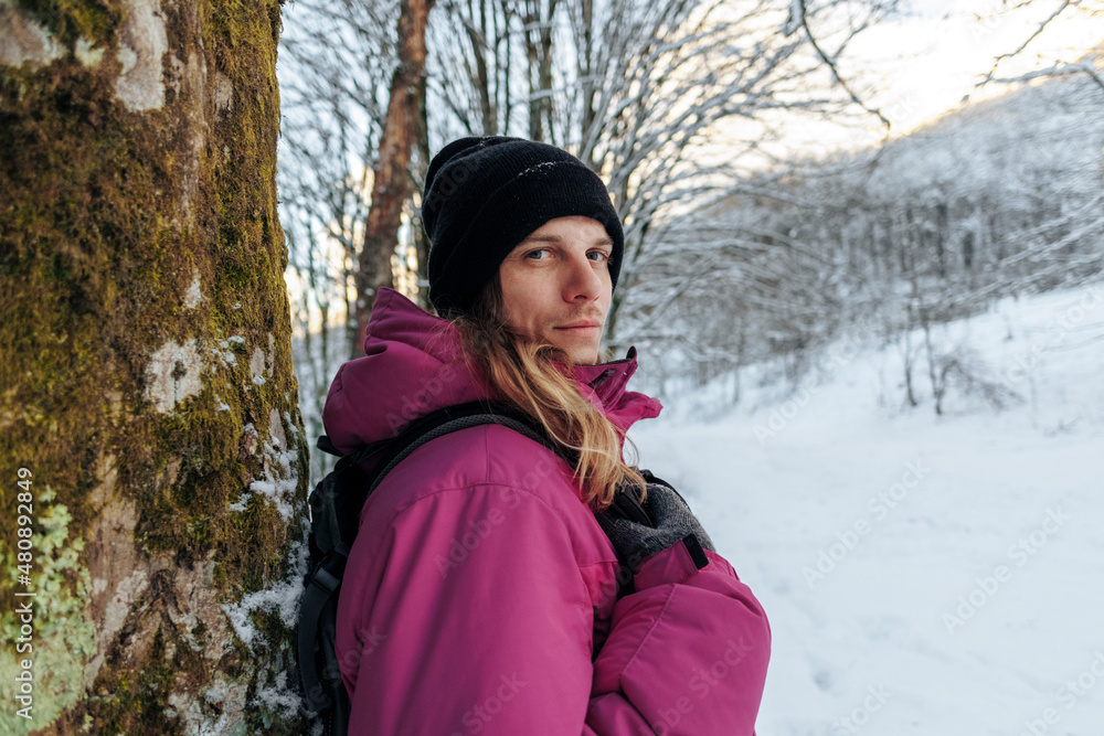 Tourist standing by tree trunk in winter vacation Tourist standing by tree trunk in winter vacation