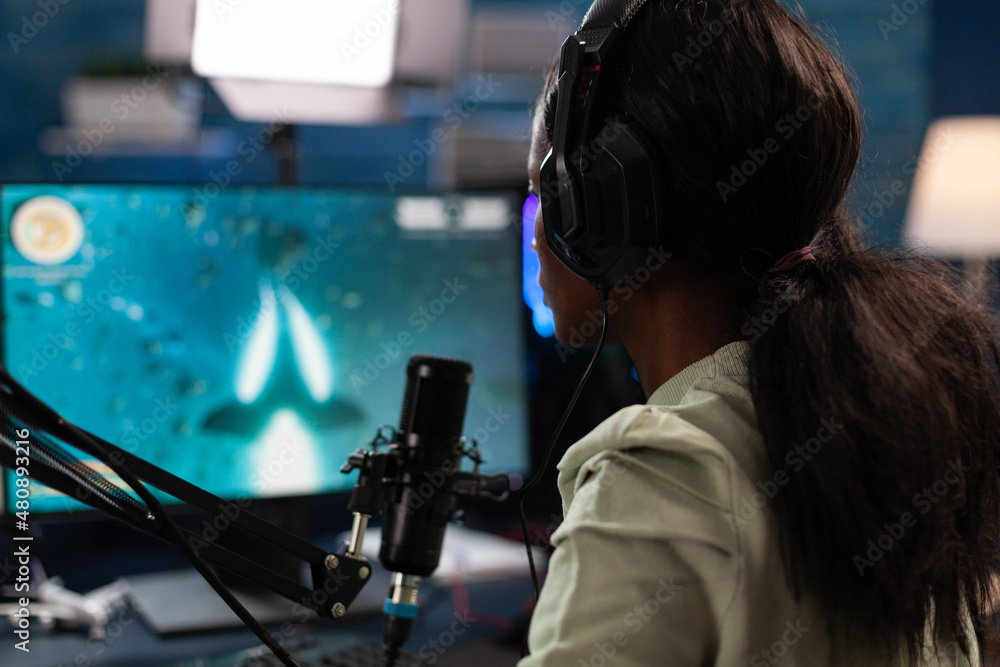 Successful esport gamer wearing headset talking with remote players during live streaming using gaming microphones. Concentrated player playing space shooter videogames during online championship Successful esport gamer wearing headset talking with remote players during live streaming using gaming microphones. Concentrated player playing space shooter videogames during online championship