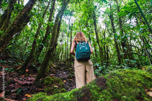 Young hiker with backpack exploring in green forest at Arenal Volcano National Park, La Fortuna, Alajuela Province, Costa Rica photo