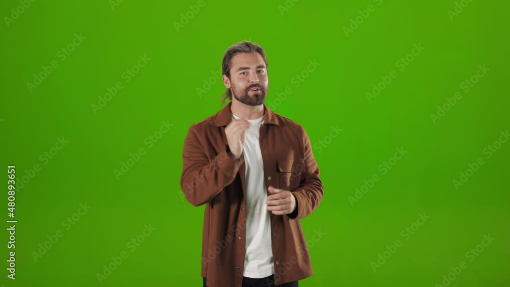 Successful bearded man in stylish wear standing over green background and gesticulating during confident speech. Concept of conference or interview. Successful bearded man in stylish wear standing over green background and gesticulating during confident speech. Concept of conference or interview.