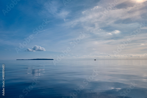 calm sea and white cloud above the island and water reflection