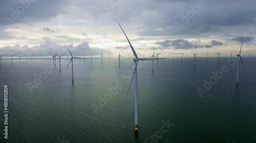 Drone video of the offshore wind turbine at Fryslan wind farm in the IJsselmeer. Dark rain clouds in the sky. Sustainable development, renewable energy, environment concept. Breezanddijk, Netherlands
