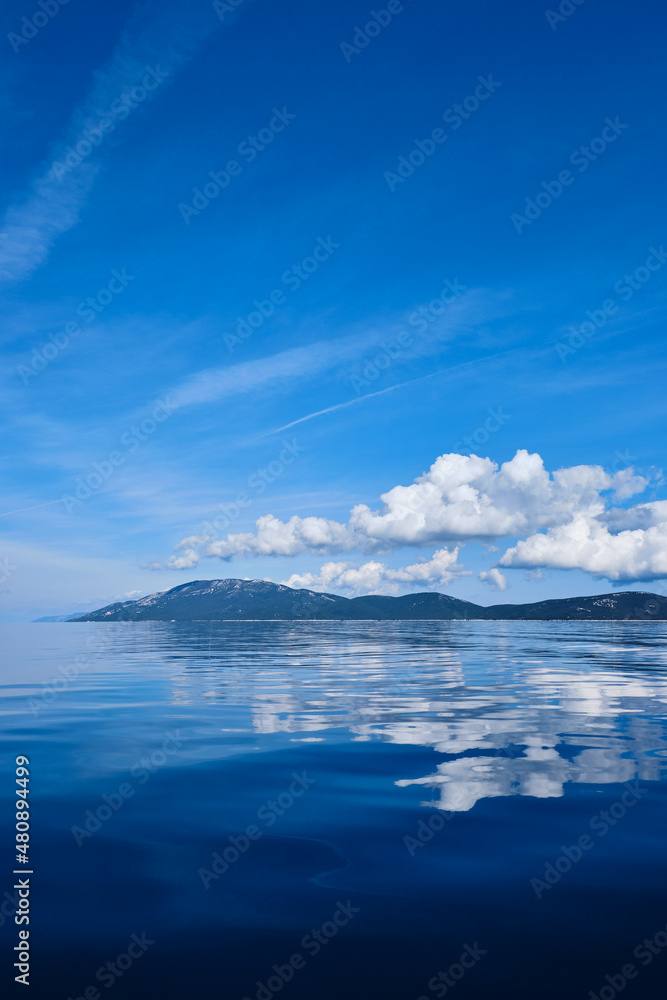 blue sky with clouds and island with water reflection