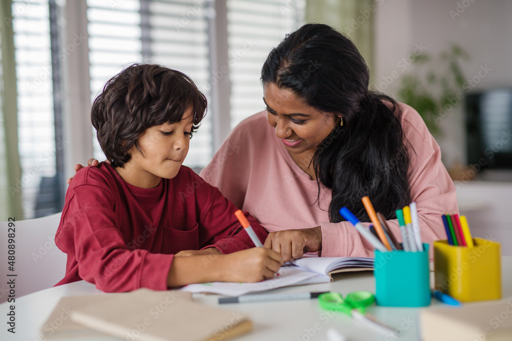 Little multiracial boy doing homework with his mother at home. Little multiracial boy doing homework with his mother at home.