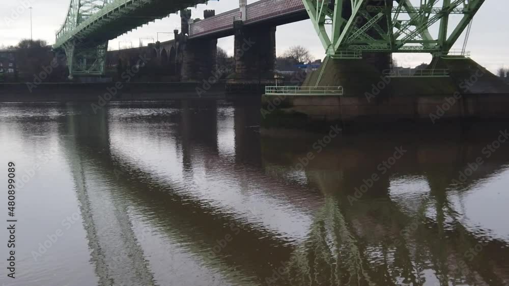 Runcorn Silver Jubilee suspension bridge reflections rippling in River Mersey below pan right Runcorn Silver Jubilee suspension bridge reflections rippling in River Mersey below pan right