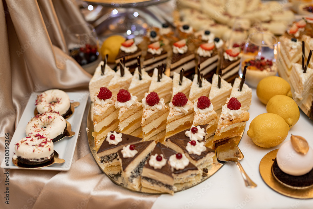 Naklejka premium Large selection of beautifully decorated and stacked desserts on sweet wedding table. Delicious dishes. Buffet festive table. Delicious pastries. Confectionery products.