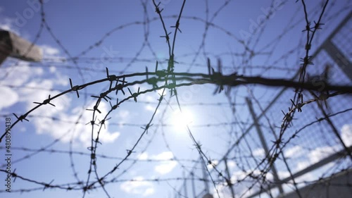 Sun rays shining through a prison barbed wire fence.