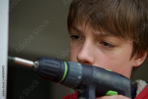caucasian teenage boy using a cordless power drill/driver