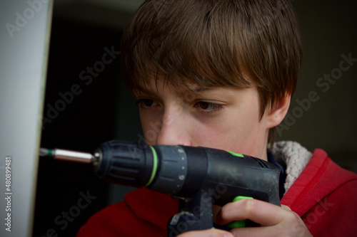 caucasian teenage boy using a cordless power drill/driver