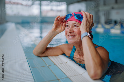 Billede på lærred Happy senior woman in swimming pool, leaning on edge.