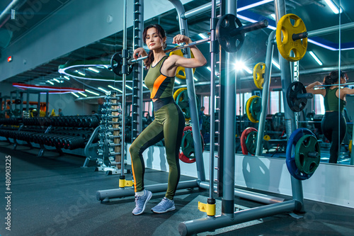 young beautiful Asian girl doing fitness exercises in the gym. she's wearing a tight-fitting suit
