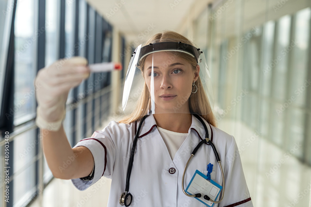 young beautiful nurse stands in the hallway in uniform and holds blood samples young beautiful nurse stands in the hallway in uniform and holds blood samples