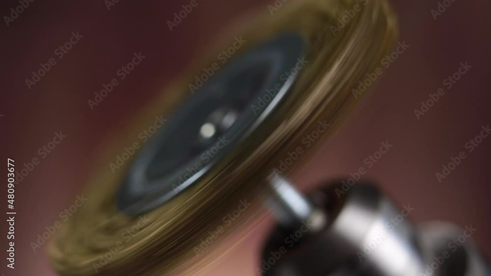 Brass wire grinder disc for drill machine. Using and testing on wooden background in slow motion. Macro. Rotation. Selective focus Brass wire grinder disc for drill machine. Using and testing on wooden background in slow motion. Macro. Rotation. Selective focus