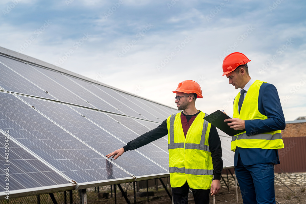 two professionals in workwear discuss solar panels and their impact. two professionals in workwear discuss solar panels and their impact.