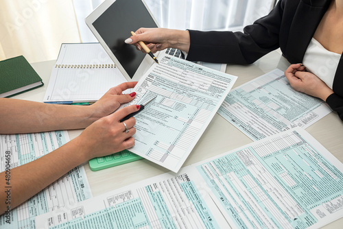 two beautiful office ladies sitting at a table and describing tax forms 1040.