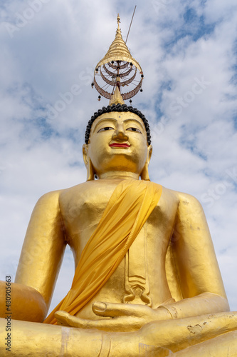 Low angle view of golden buddha statue on blue sky with clouds background at historic ancient Wat Chiang Yuen buddhist temple  Chiang Mai  Thailand
