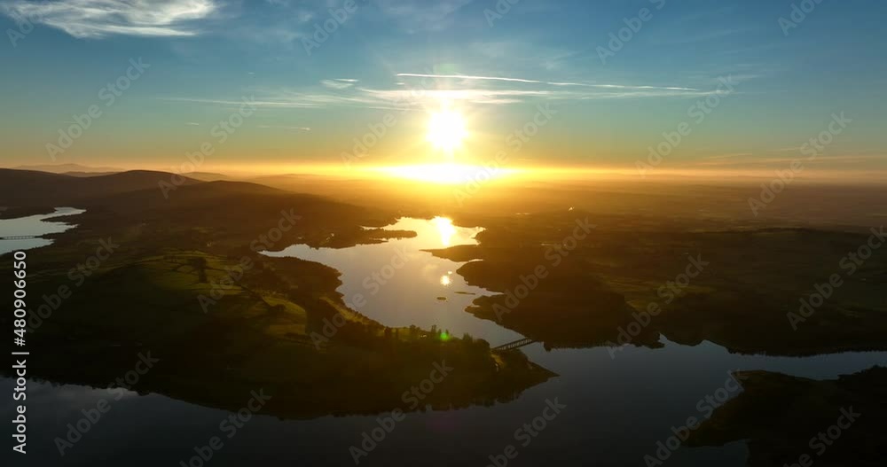 Blessington Lakes, Wicklow, Ireland. January 2022 Drone pushes towards Boystown above the Poulaphouca reservoir while descending from the northeast with a golden wintery sunset on the horizon. Blessington Lakes, Wicklow, Ireland. January 2022 Drone pushes towards Boystown above the Poulaphouca reservoir while descending from the northeast with a golden wintery sunset on the horizon.