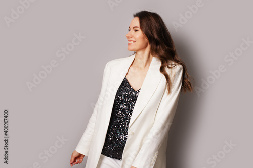 Young pretty brunette woman in white jacket and sequins t-shirt, smiling photo