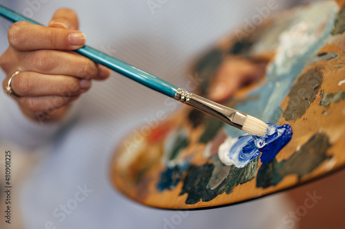 Closeup picture of a woman mixing white and blue on her palette.