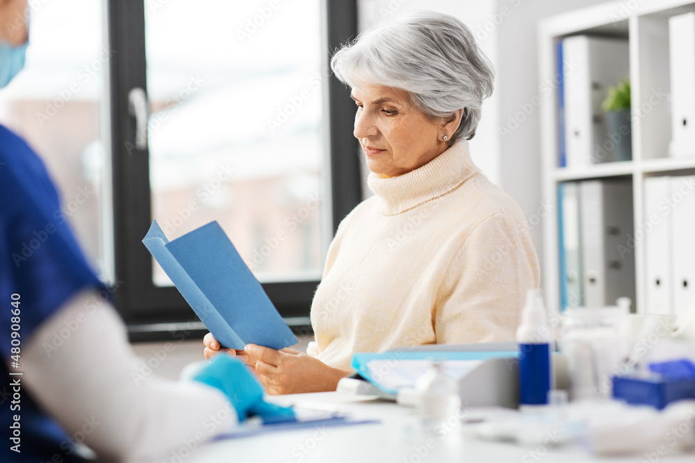 medicine, health and vaccination concept - doctor or nurse and senior woman reading medical brochure at hospital medicine, health and vaccination concept - doctor or nurse and senior woman reading medical brochure at hospital