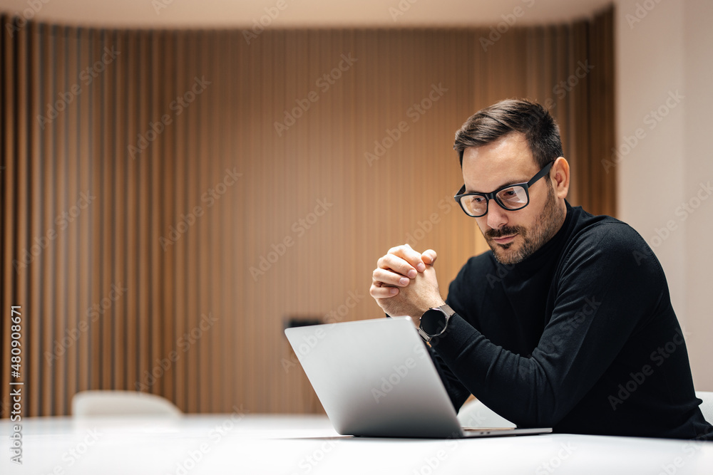 Adult serious businessman, working in the company office on a laptop. - obrazy, fototapety, plakaty 