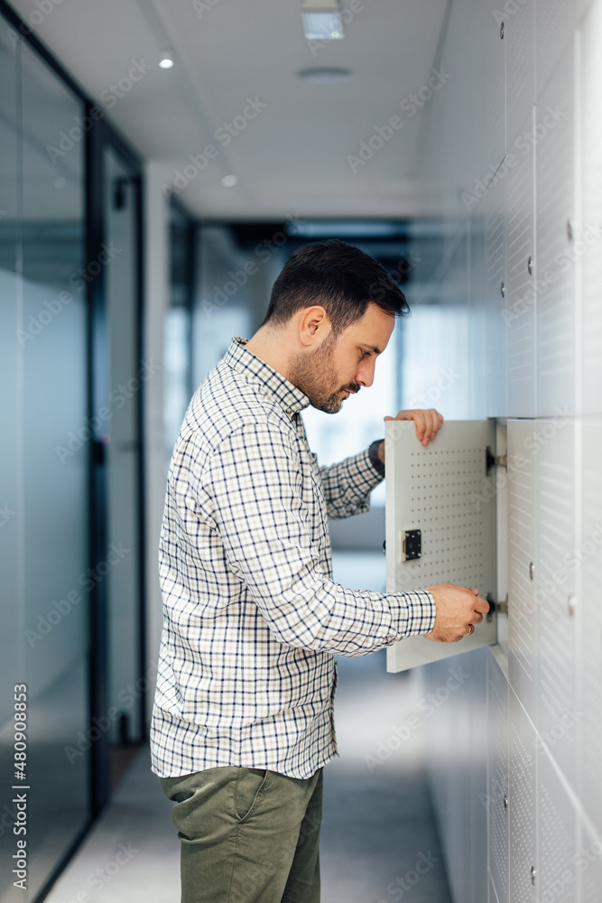Serious caucasian man, taking his belongings out of the locker.
