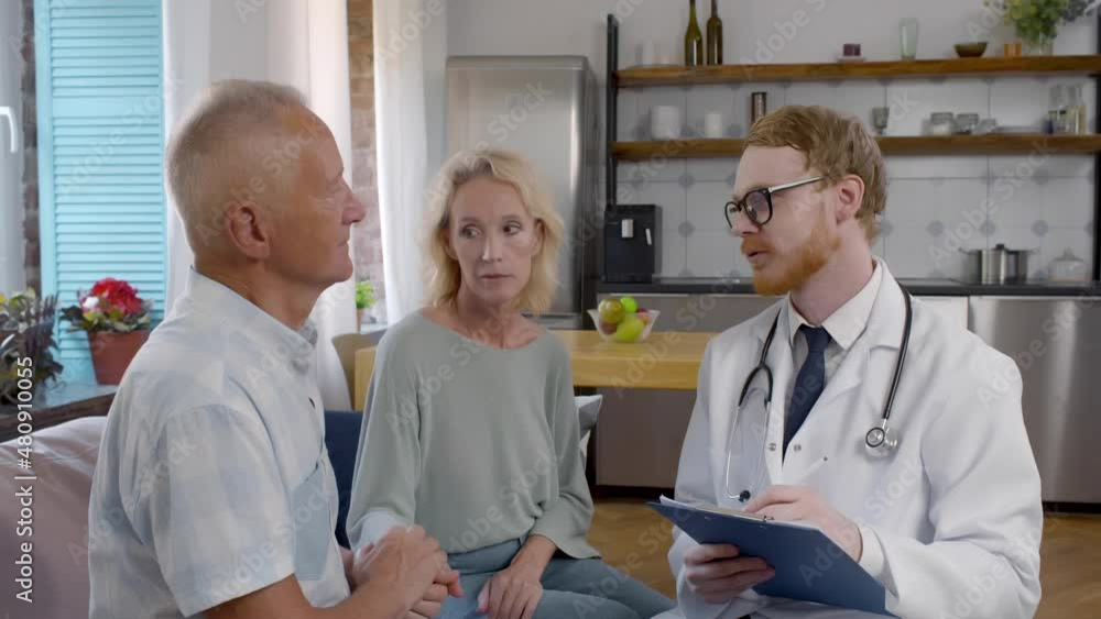 Doctor consulting senior couple during home visit. Realtime Doctor consulting senior couple during home visit. Realtime
